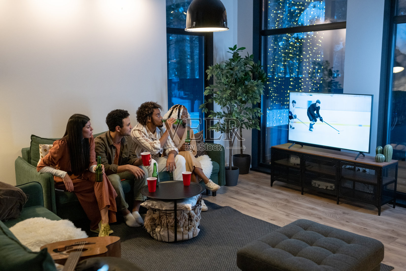 朋友们在电视上看体育比赛照片摄影图片