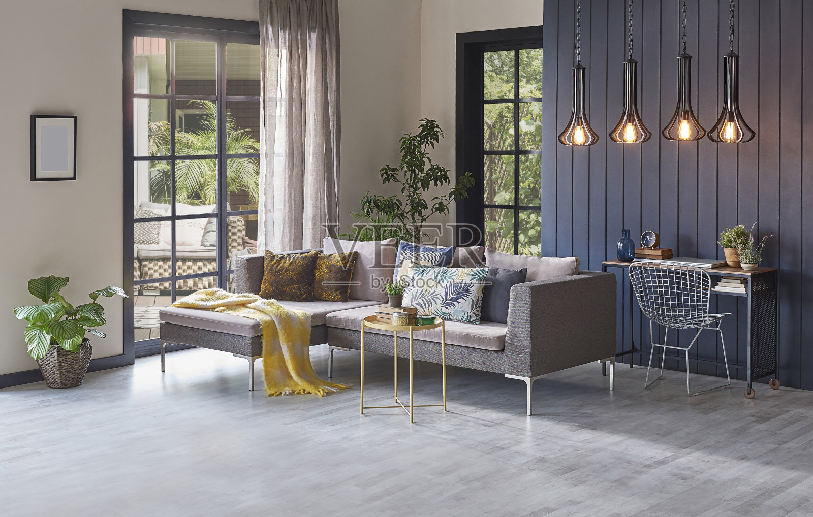 花园景观前的现代灰色沙发和木制背景墙，植物灯花瓶和中间的桌子，家居设计。照片摄影图片