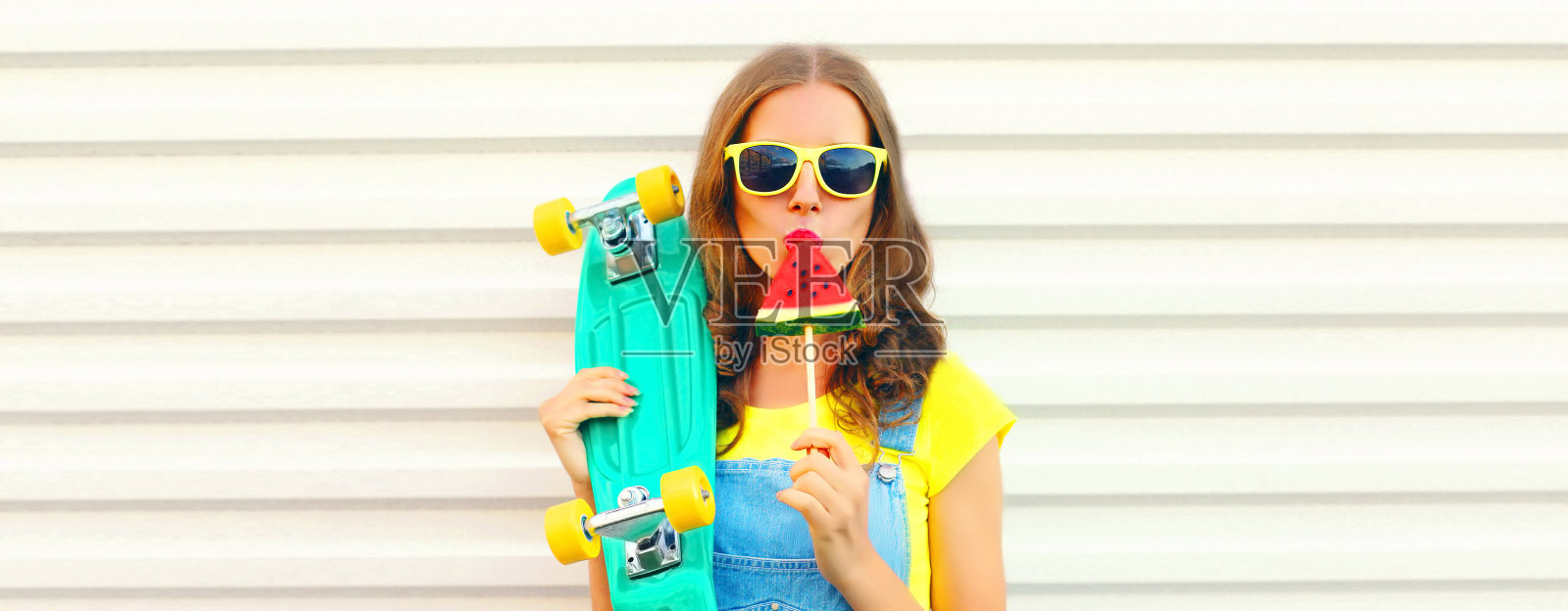 夏天的肖像年轻女子与滑板吃冰淇淋形状的西瓜片在白色的背景照片摄影图片