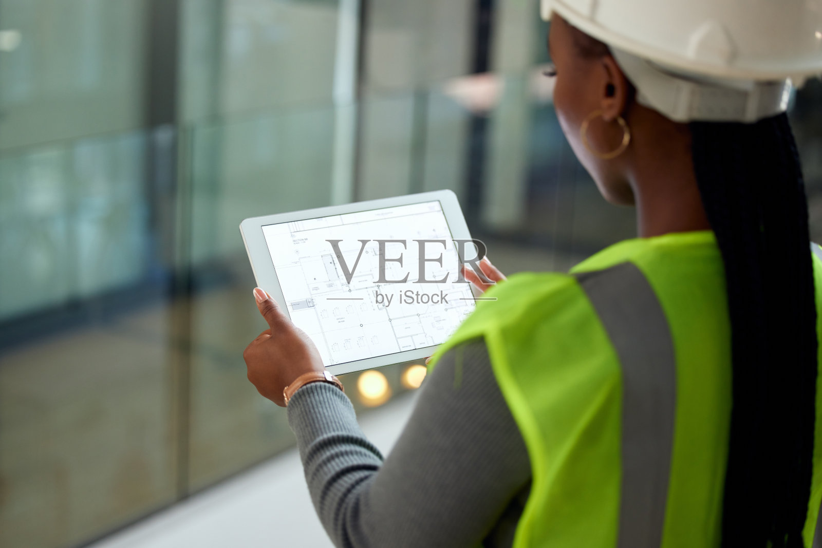 一个不知名的女建筑师站在她的办公室里使用平板电脑的后视镜照片摄影图片