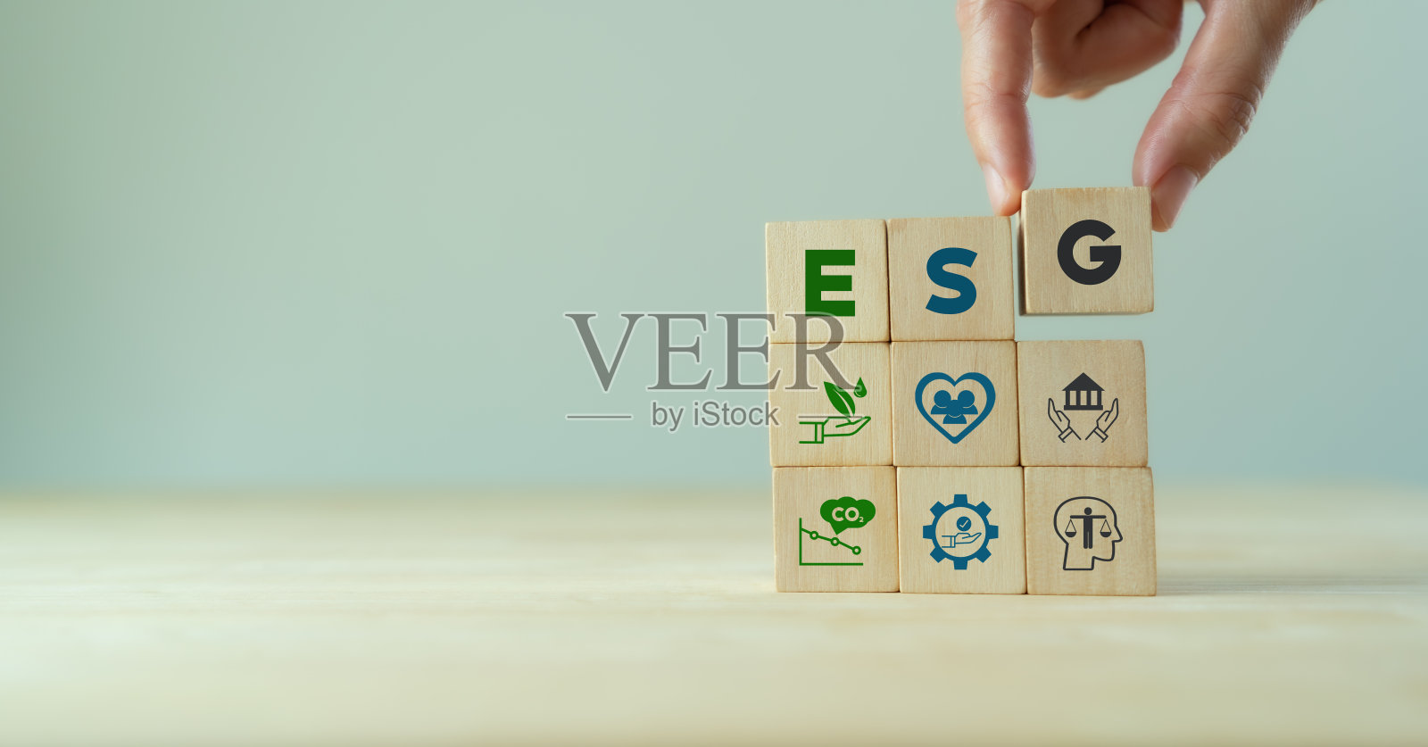 环境、社会和治理的ESG概念。公司可持续发展。手握木制立方体与缩写ESG站立与其他ESG图标在灰色背景。副本的空间。照片摄影图片