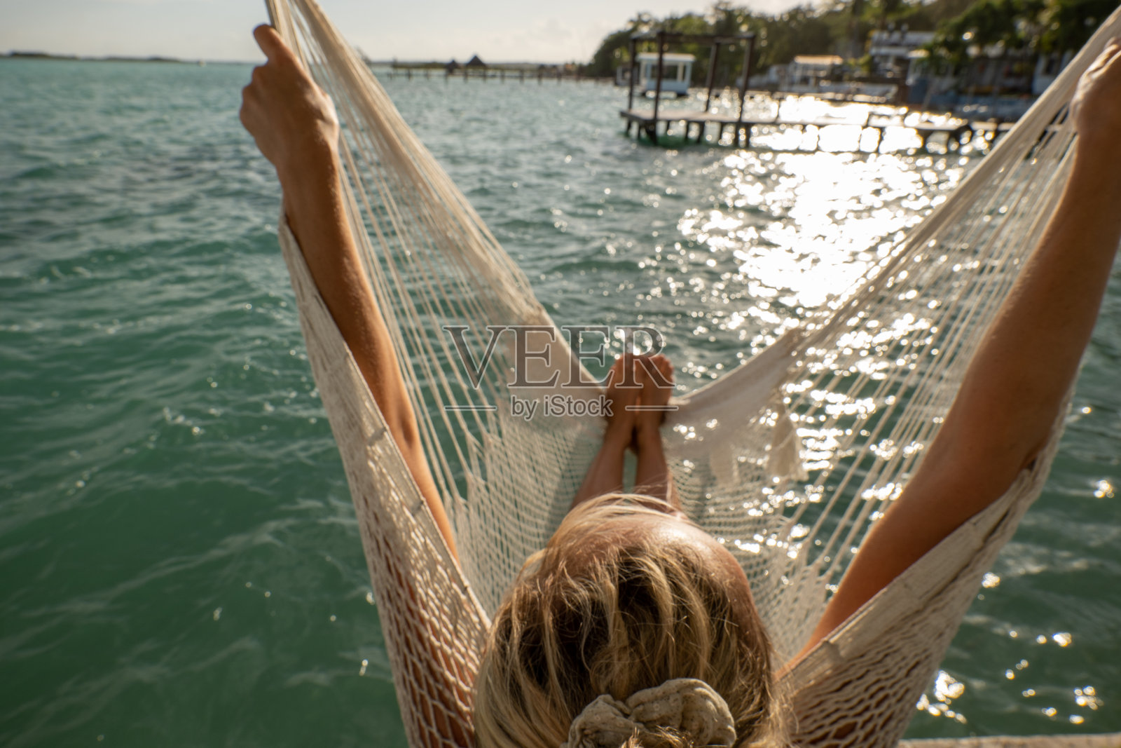 一个女人放松地坐在吊椅上看湖面上的日出照片摄影图片