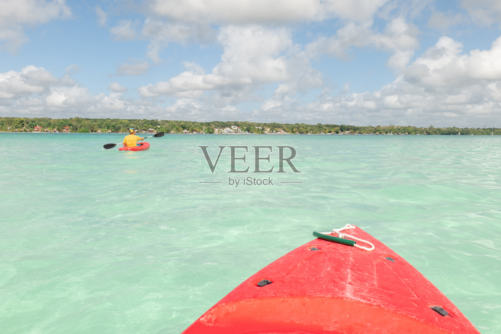 男游客在热带泻湖上划独木舟，女朋友在沙滩上照片摄影图片