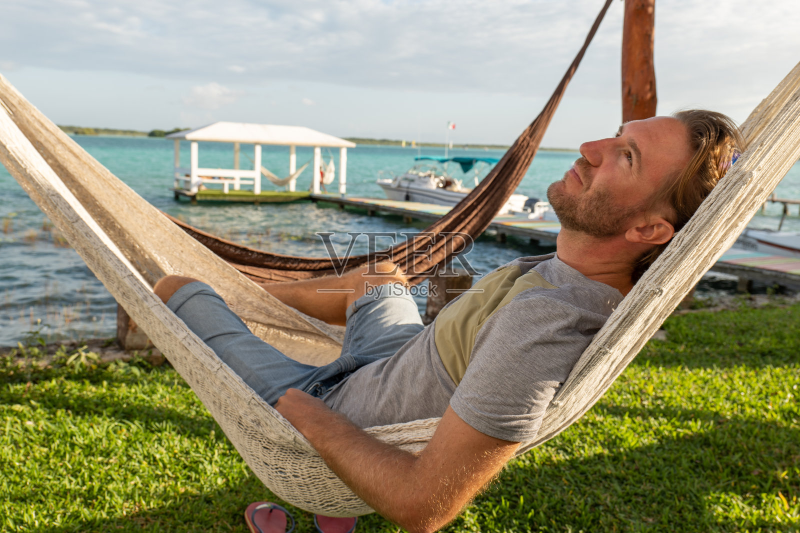 日落时分躺在吊床上的男人，湖光山色照片摄影图片