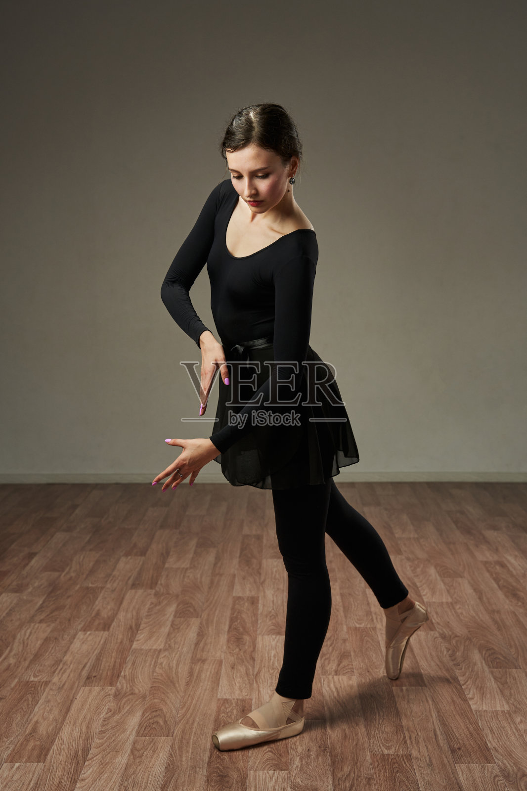 舞蹈演员优雅地将双手放在身前，脚侧向一边。舞蹈之美与优雅。照片摄影图片