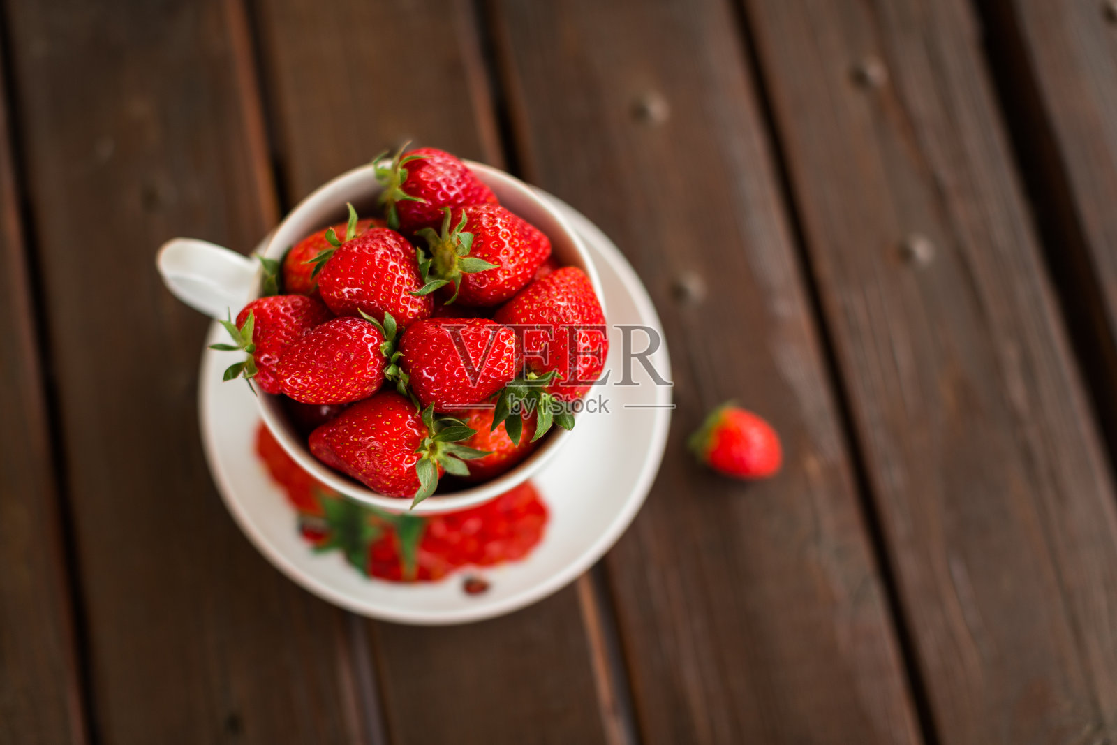木桌上放着一大杯新鲜草莓照片摄影图片