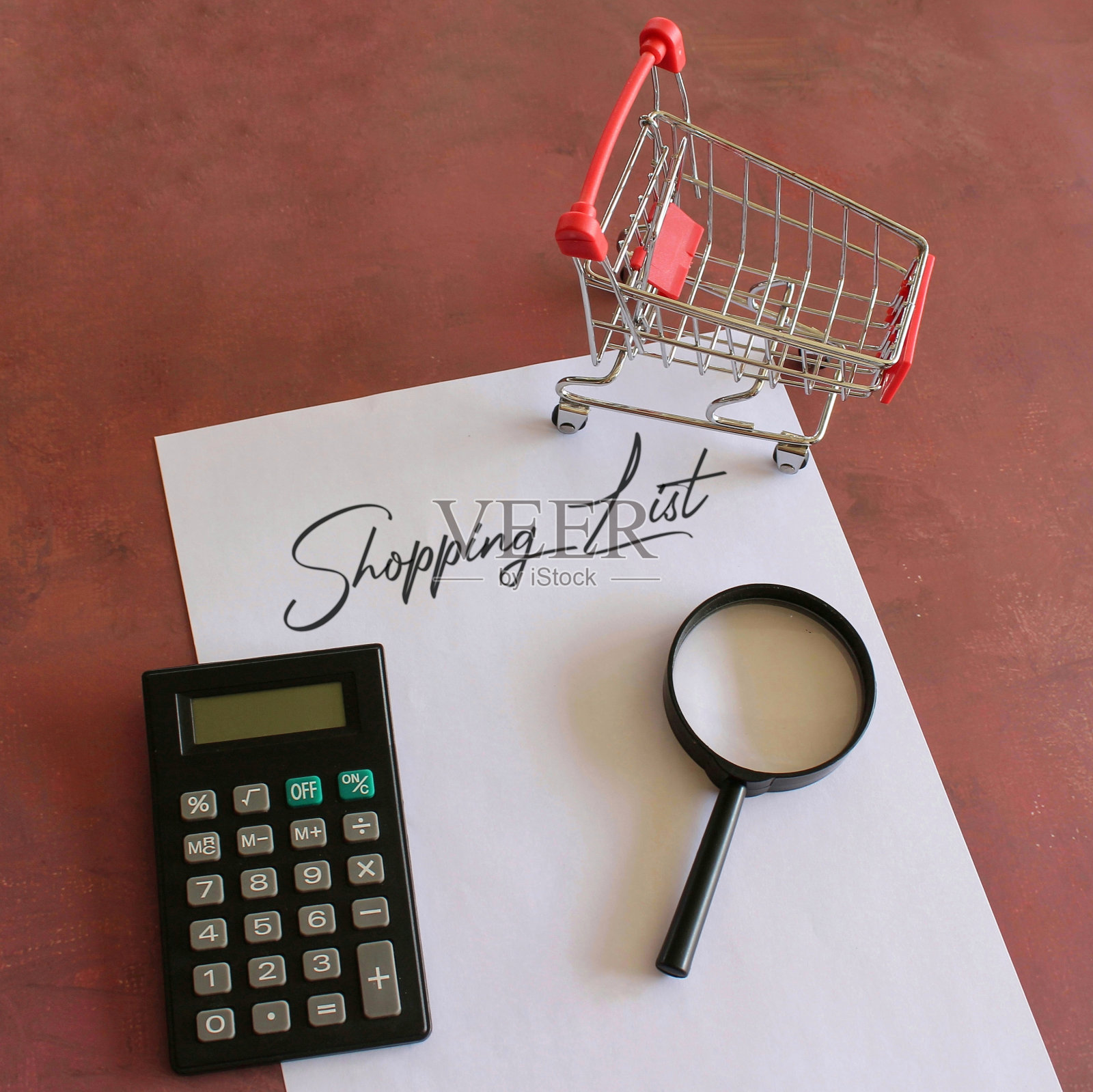 计算器，购物车，放大镜和纸与文字购物清单。照片摄影图片