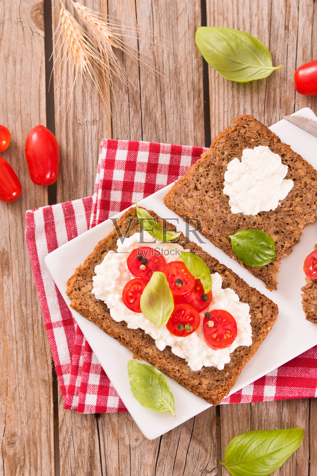 黑麦面包配白软干酪，罗勒和番茄。照片摄影图片