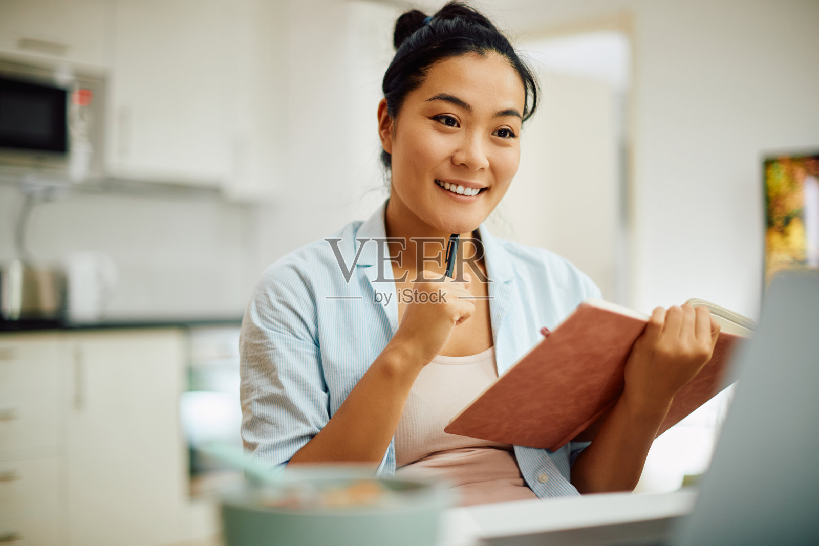 年轻快乐的亚洲妇女在家里学习时使用电脑。照片摄影图片