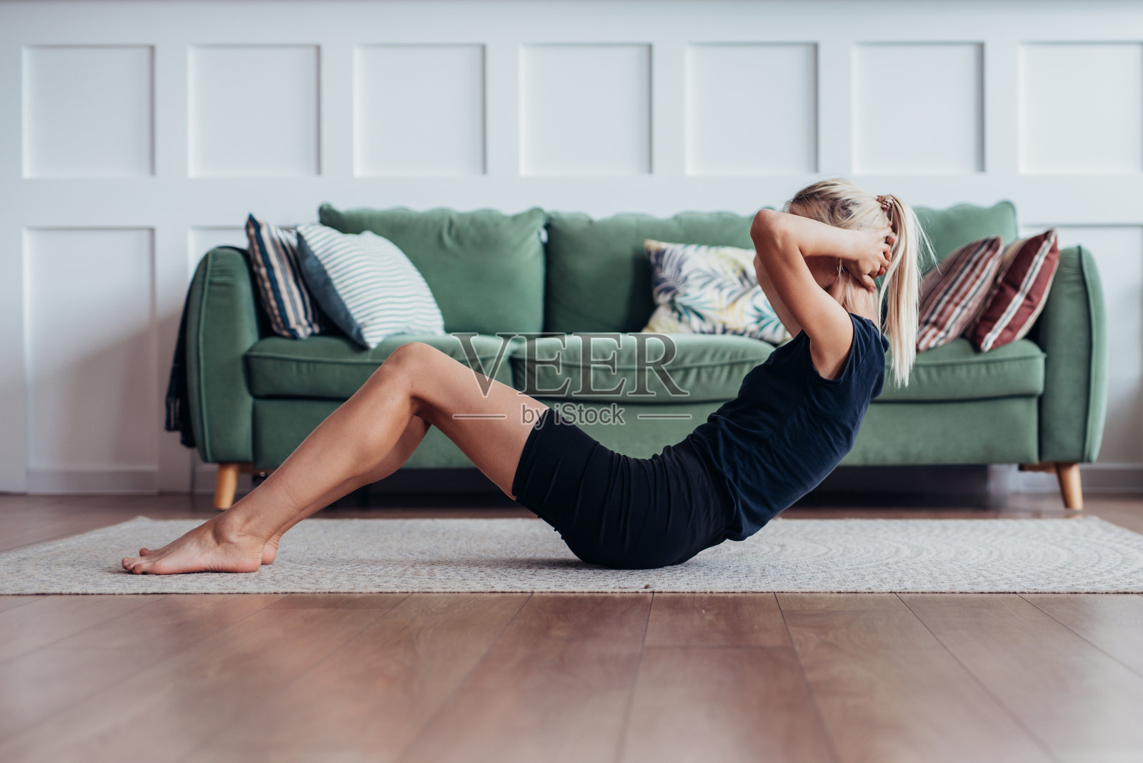 健身女士在做仰卧起坐。年轻女子在家做腹部锻炼。照片摄影图片