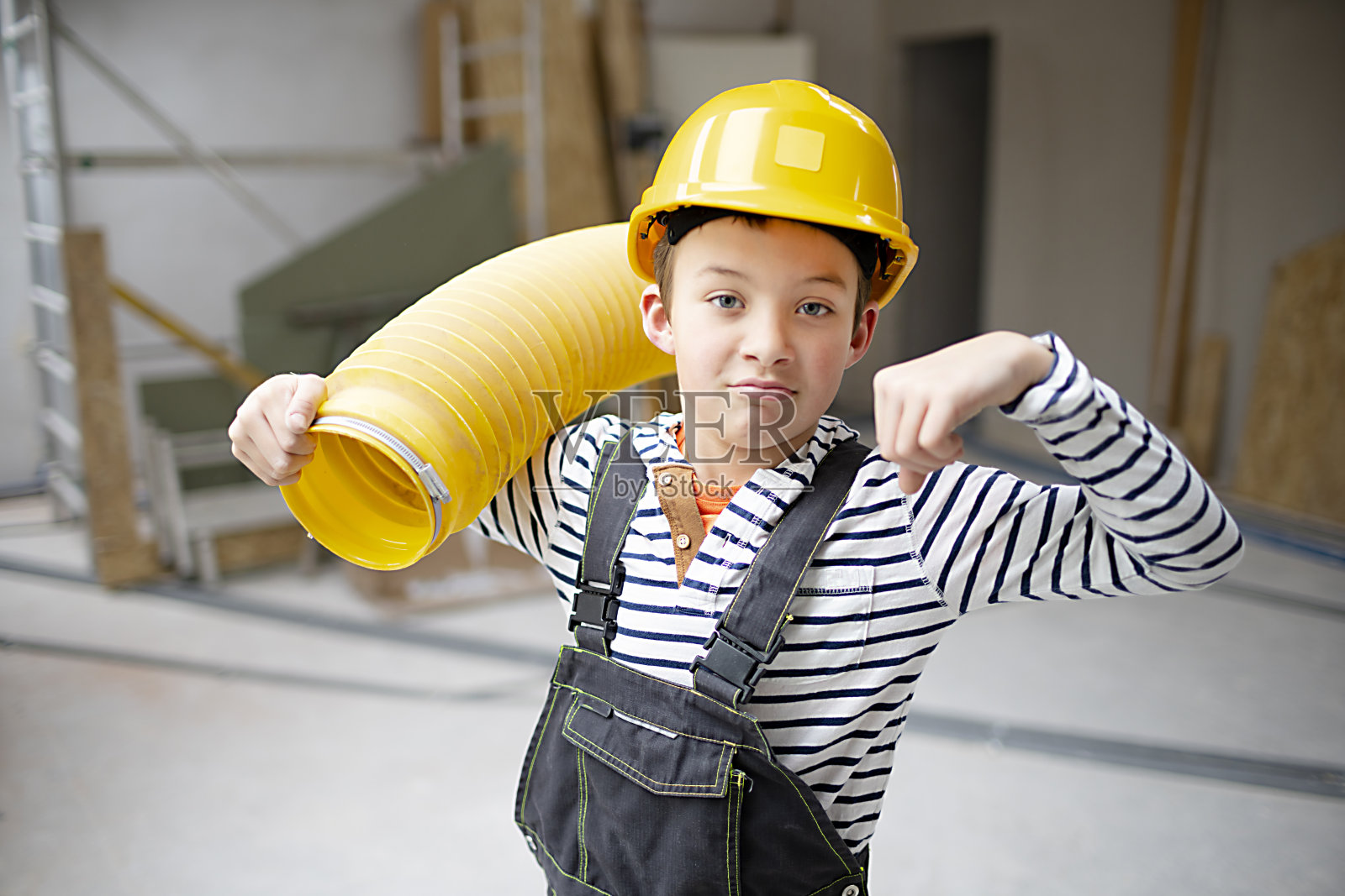 工地上戴黄色安全帽、管黄色管子的酷小子照片摄影图片