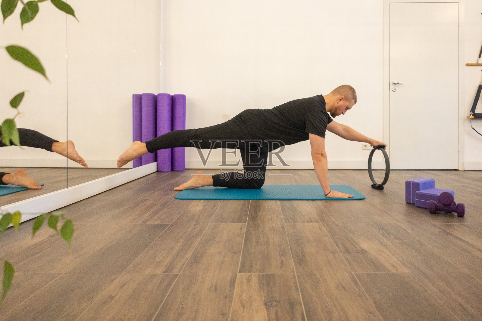 男性健身普拉提教练在特殊的模拟器上展示练习。伸缩橡胶圈照片摄影图片