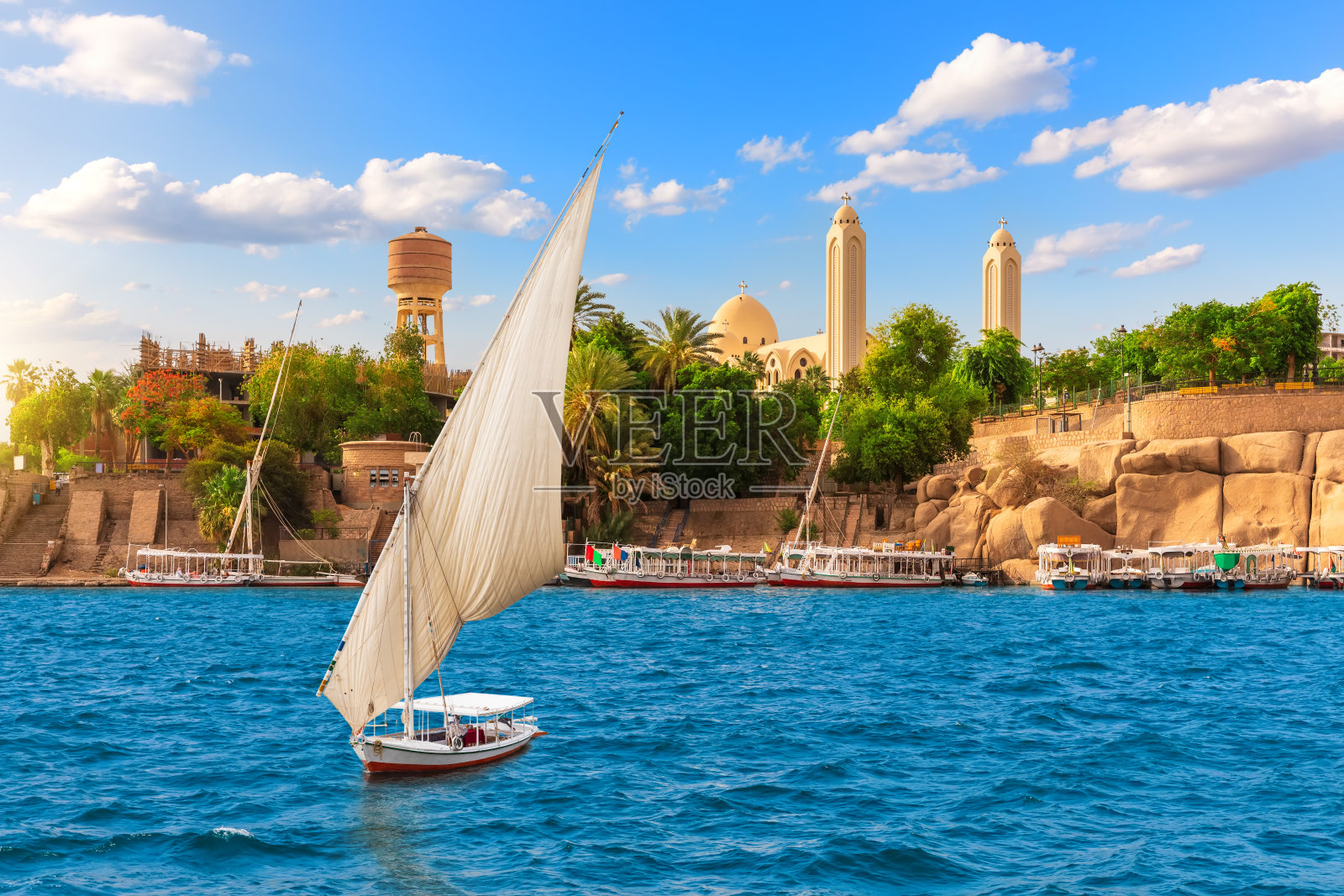 埃及阿斯旺天使长米迦勒科普特东正教大教堂附近的尼罗河上的帆船照片摄影图片