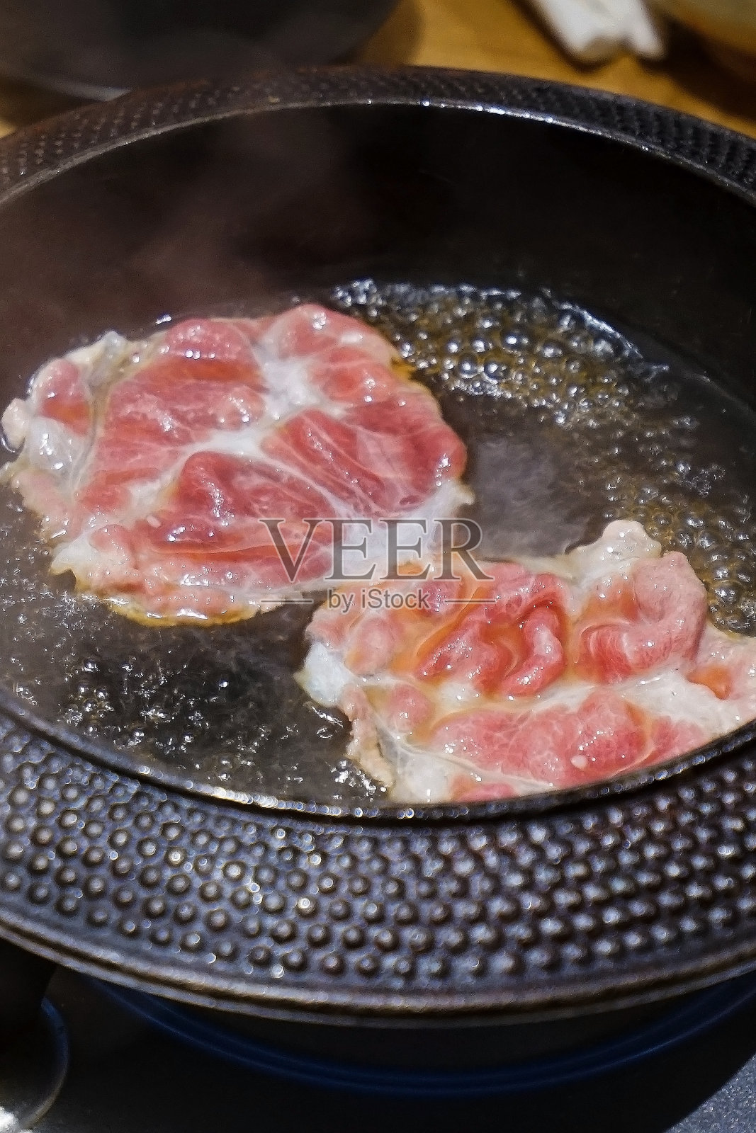木制的桌子上摆满了蔬菜，切片的和牛和猪肉，米饭，生鸡蛋和蘸酱照片摄影图片