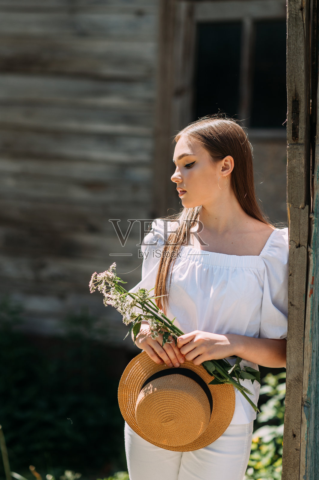 一个年轻的女孩穿着白色的连衣裙和帽子在夏天散步。照片摄影图片