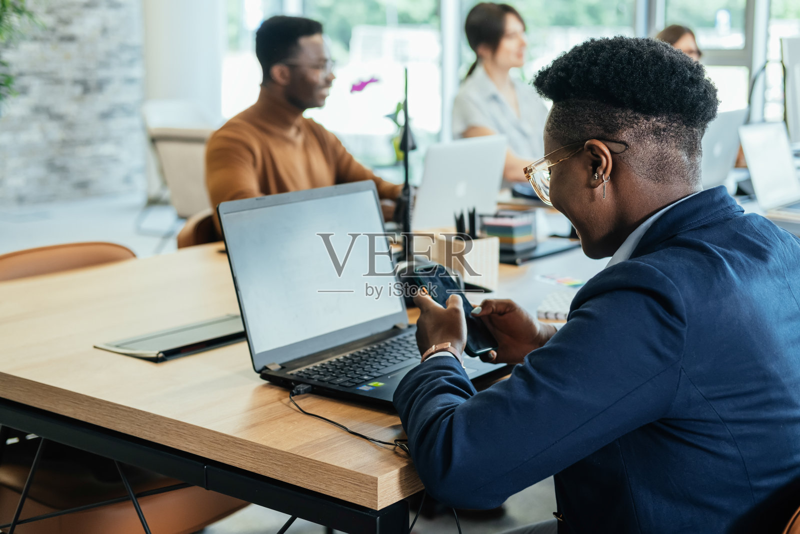 一位匿名的商业女性在开放式办公室使用移动电话照片摄影图片