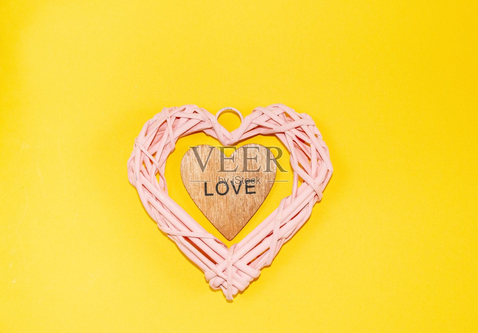 美丽的粉色柳条心由天然藤枝制成，配上节日饰品、玻璃玩具和装饰品，用于情人节或妇女节的概念祝贺、爱情告白。照片摄影图片