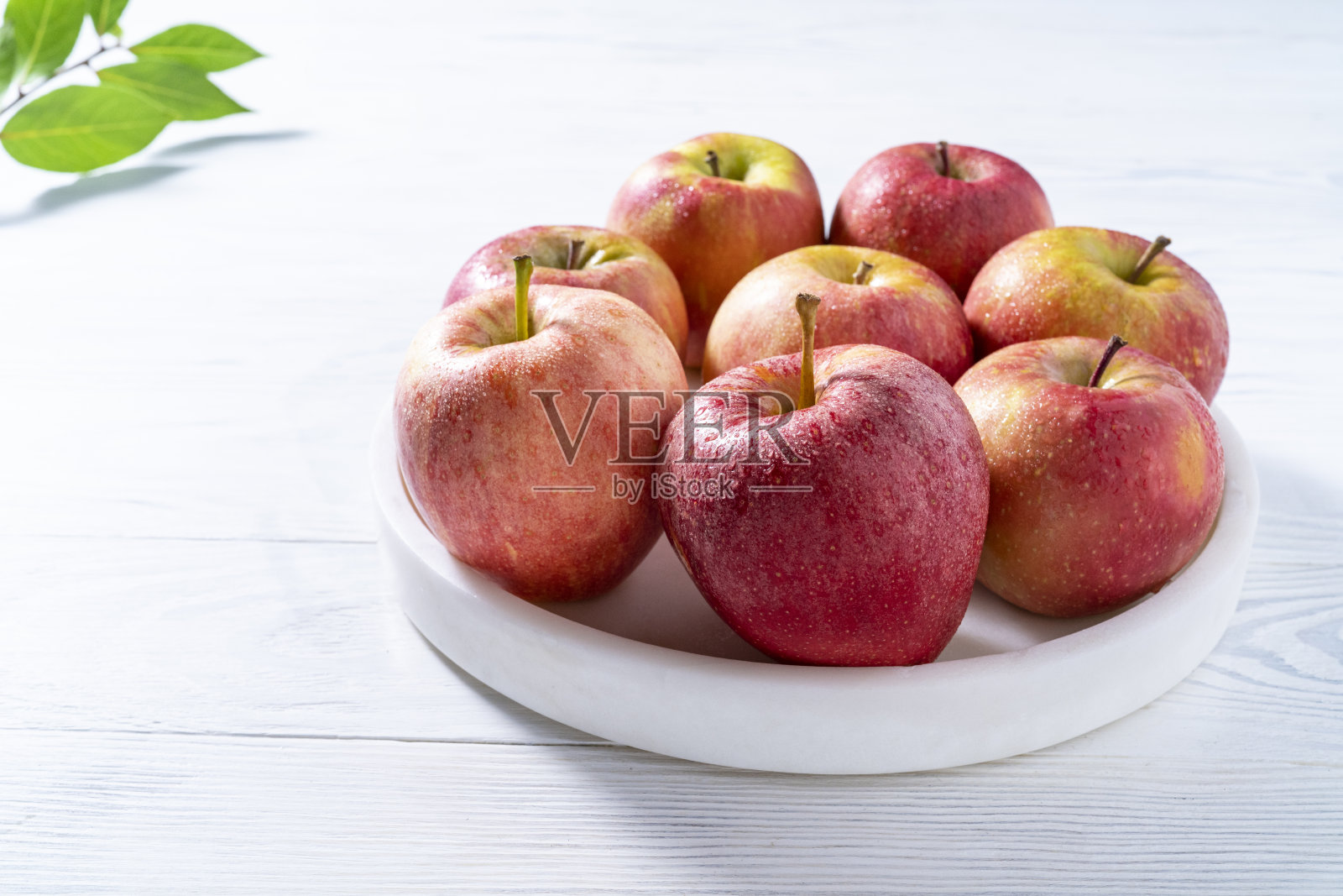 红色的苹果在大理石板上白色的木材背景新鲜和潮湿的露珠照片摄影图片