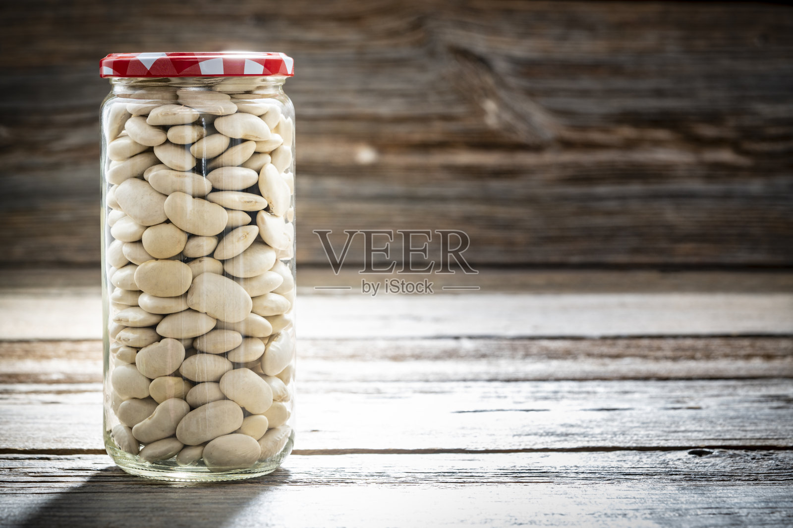 干燥的大白豆，蚕豆，豆类在一个玻璃罐特写孤立在乡村木材照片摄影图片