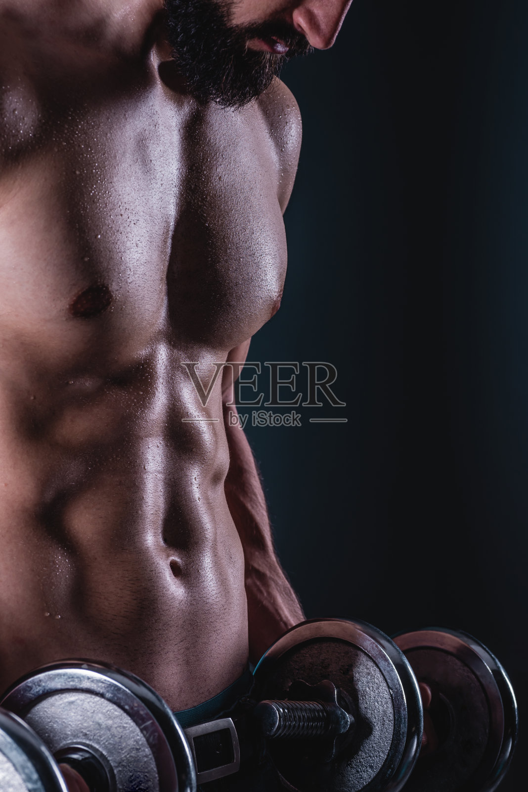 举重的强壮肌肉男。英俊的大胡子潮男拿着哑铃。照片摄影图片