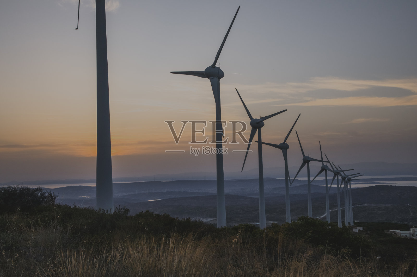 在阳光明媚的夏天，阳光明媚的时间里，鸟瞰农村绿地上的大型生态系统、风力涡轮机和发电站。照片摄影图片