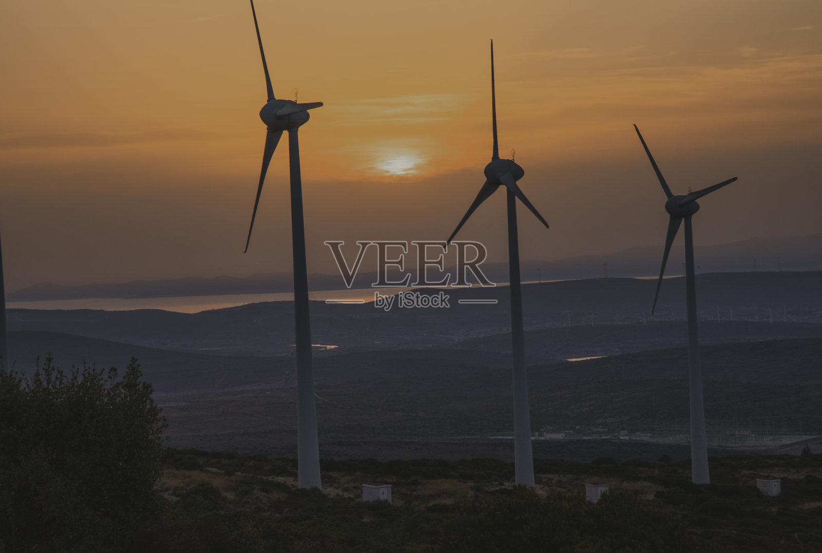 在阳光明媚的夏天，阳光明媚的时间里，鸟瞰农村绿地上的大型生态系统、风力涡轮机和发电站。照片摄影图片