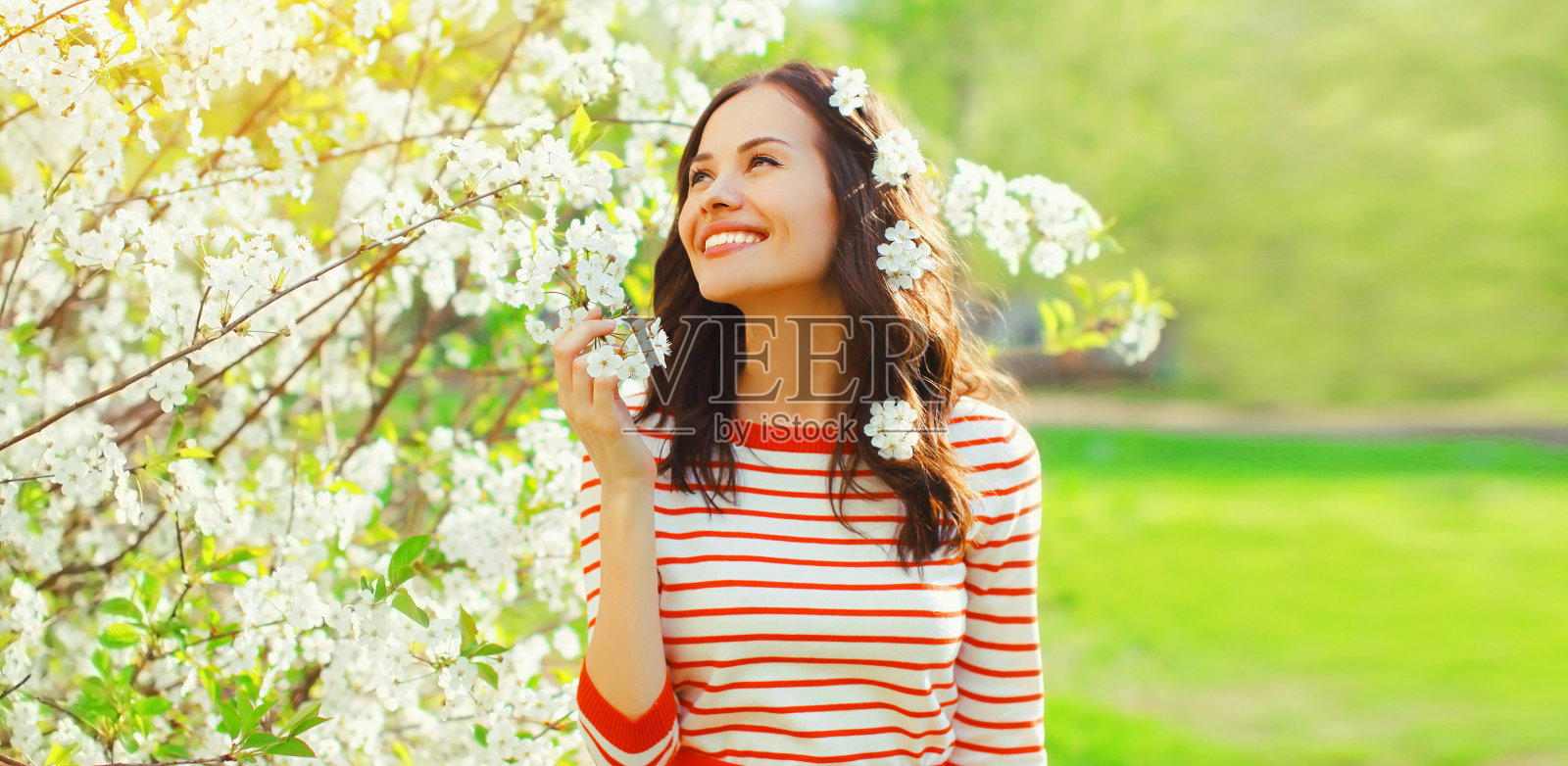 美丽可爱的年轻女子的肖像在春天盛开的花园白花的背景照片摄影图片