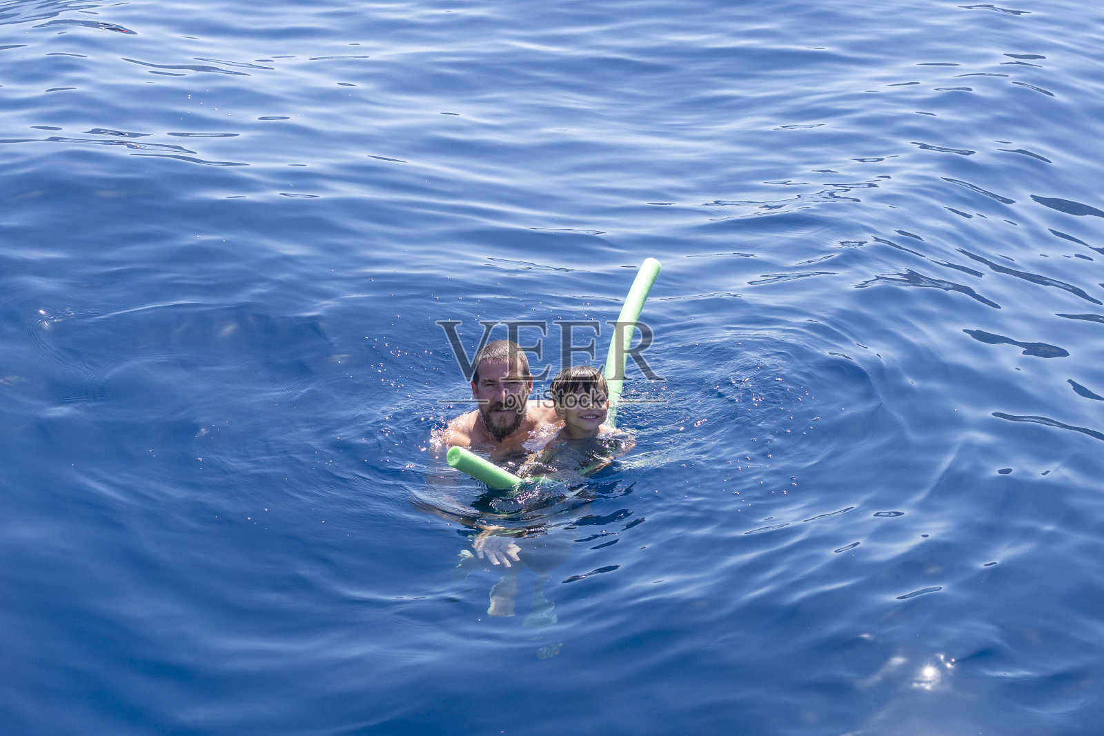 父亲教儿子在海里游泳照片摄影图片