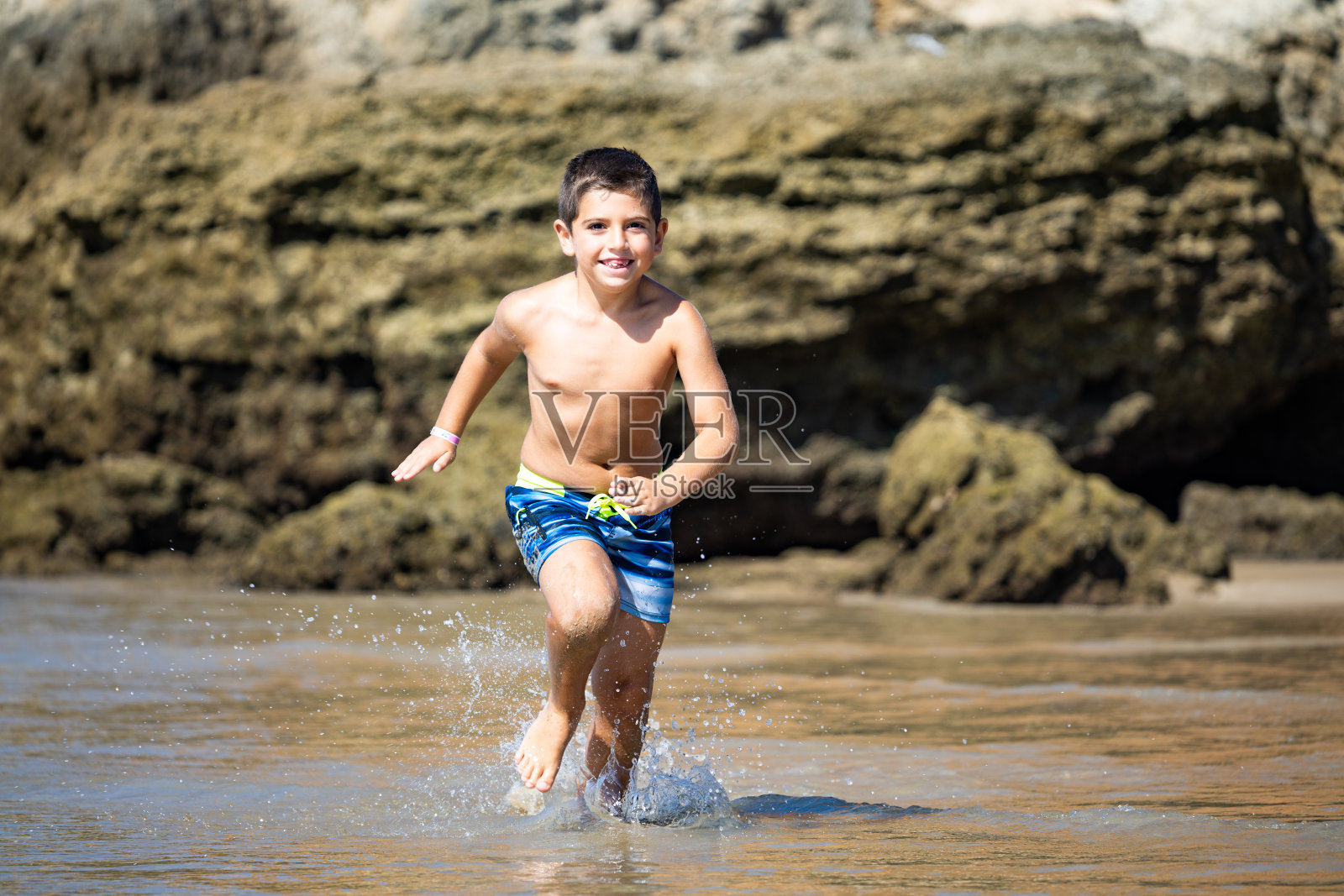 一个小孩在岩石沙滩上奔跑照片摄影图片