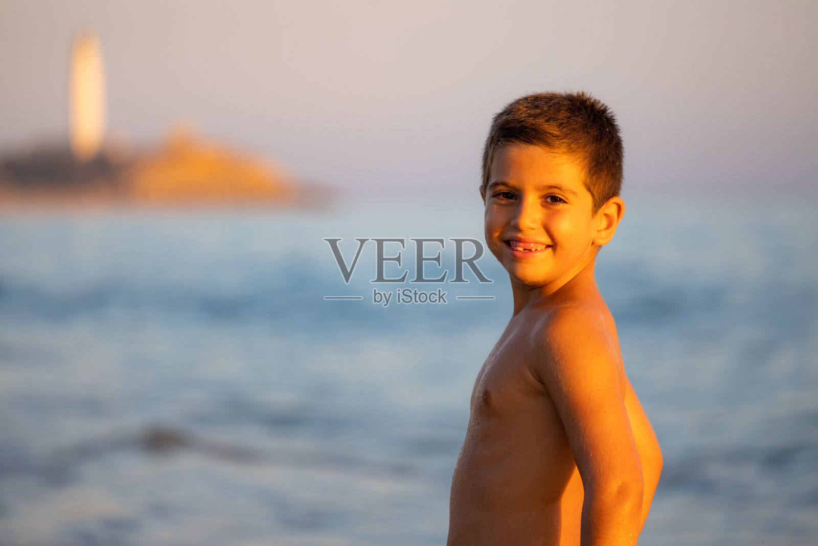 一个可爱的男孩在sinset海滩上的肖像照片摄影图片