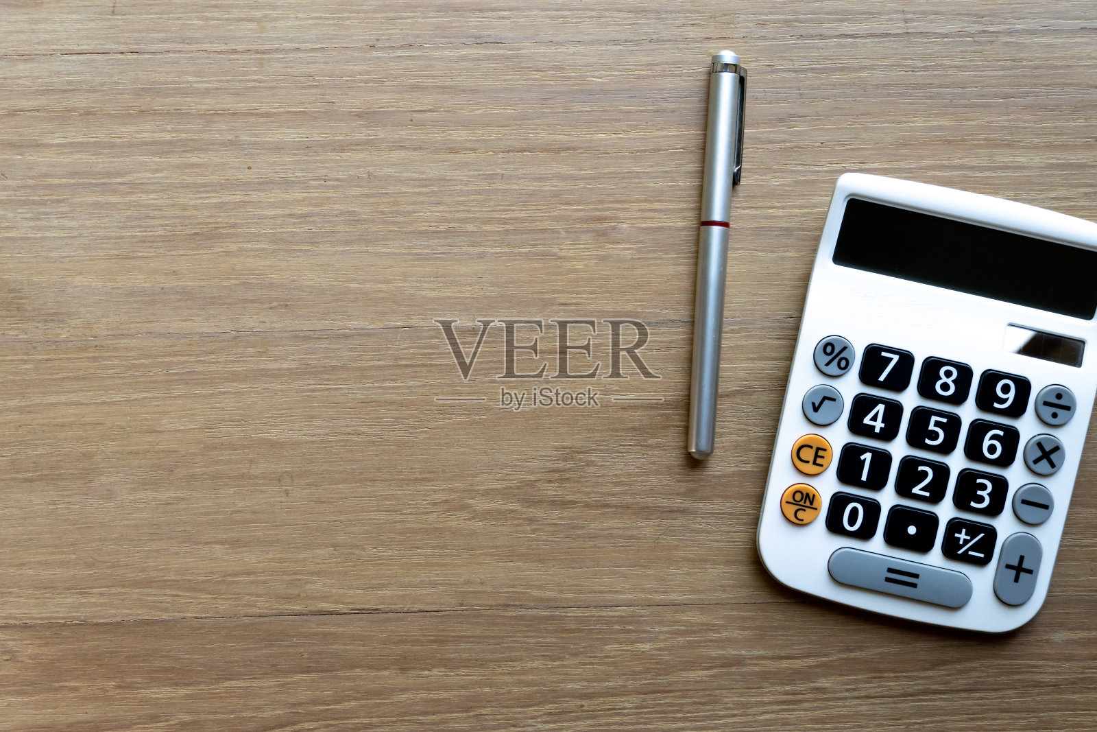 桌面上的笔和计算器在木制的表面。有花钱的概念和财务背景照片摄影图片