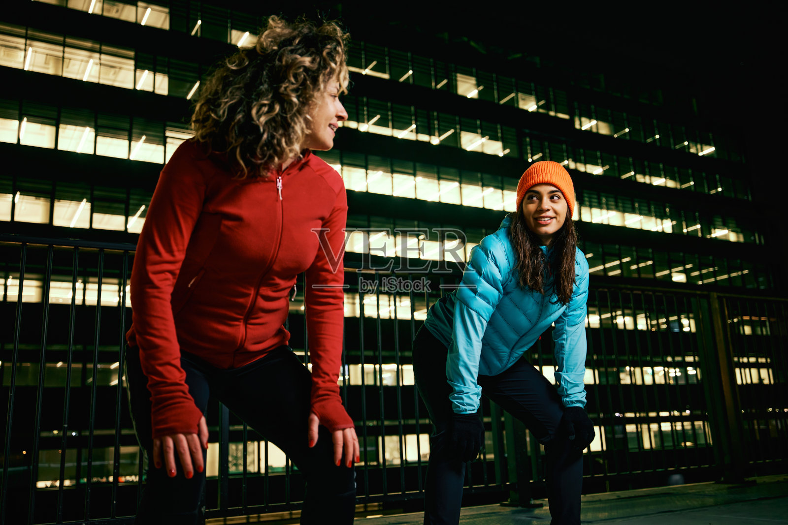 两名女性夜间跑步者在火车站休息。照片摄影图片