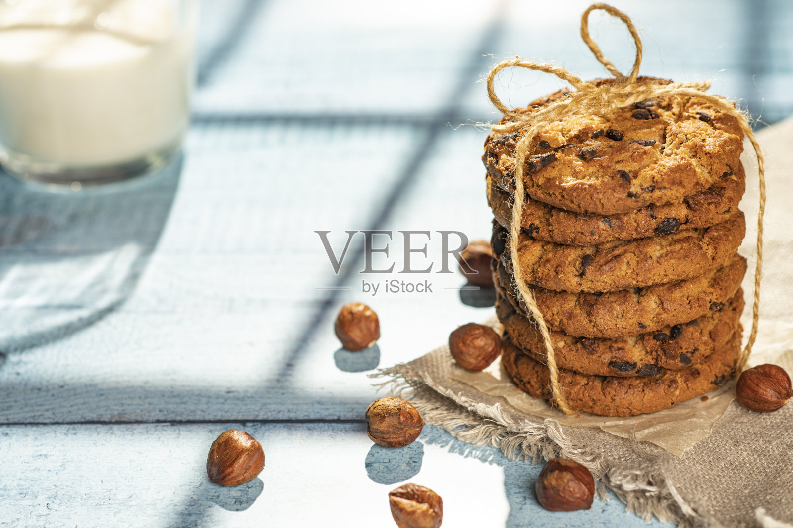 木桌上放着自制的饼干，里面有葡萄干、巧克力、坚果和牛奶，还有一个艺术品电话。早餐。关闭了。照片摄影图片