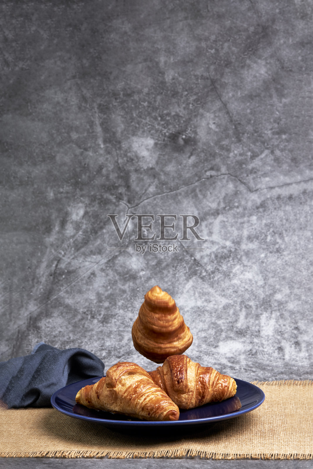 一群牛角面包掉在蓝色盘子上。糖果和甜点照片摄影图片