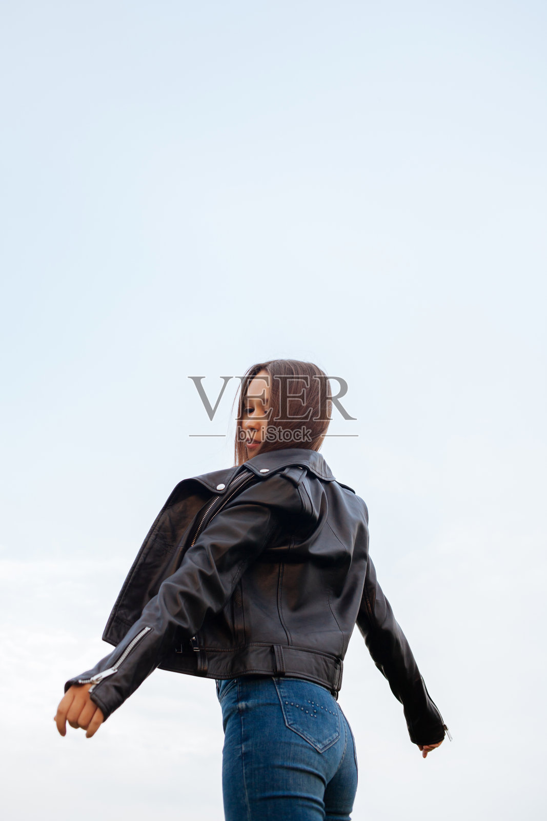 年轻的黑发女人穿着皮夹克和牛仔裤在大自然中照片摄影图片