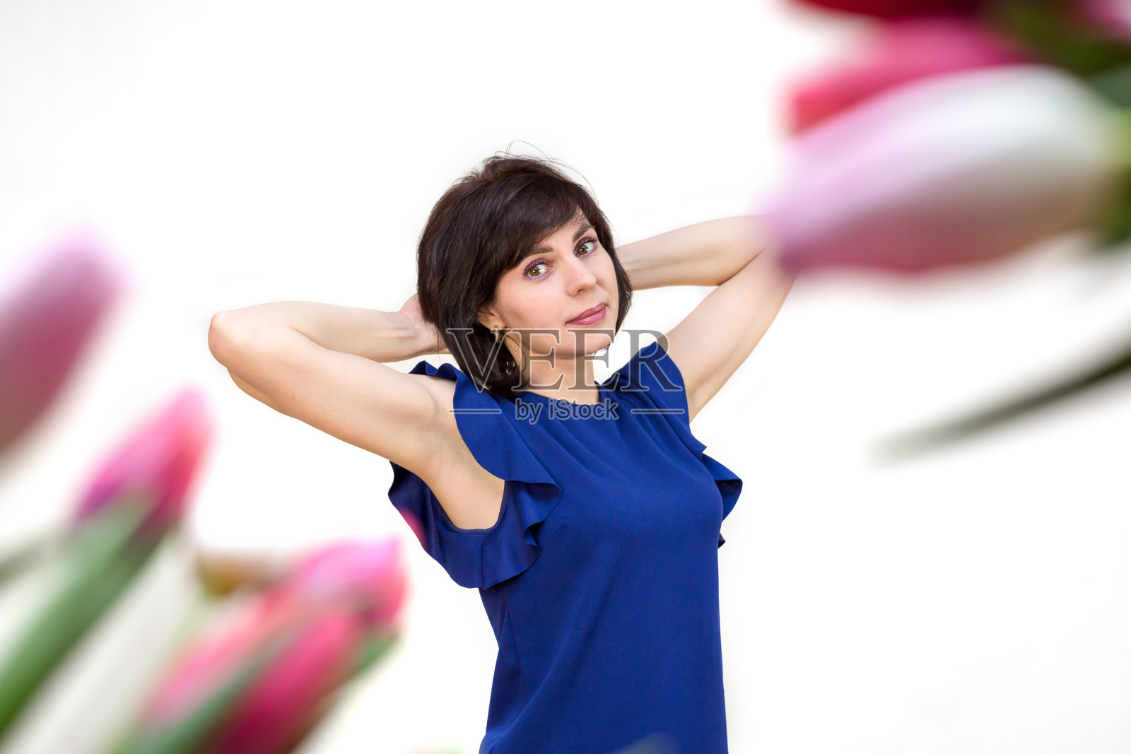 一个35-40岁的黑发女人穿着一件蓝色的衬衫，背景是春天的郁金香。孤立的,白色背景照片摄影图片