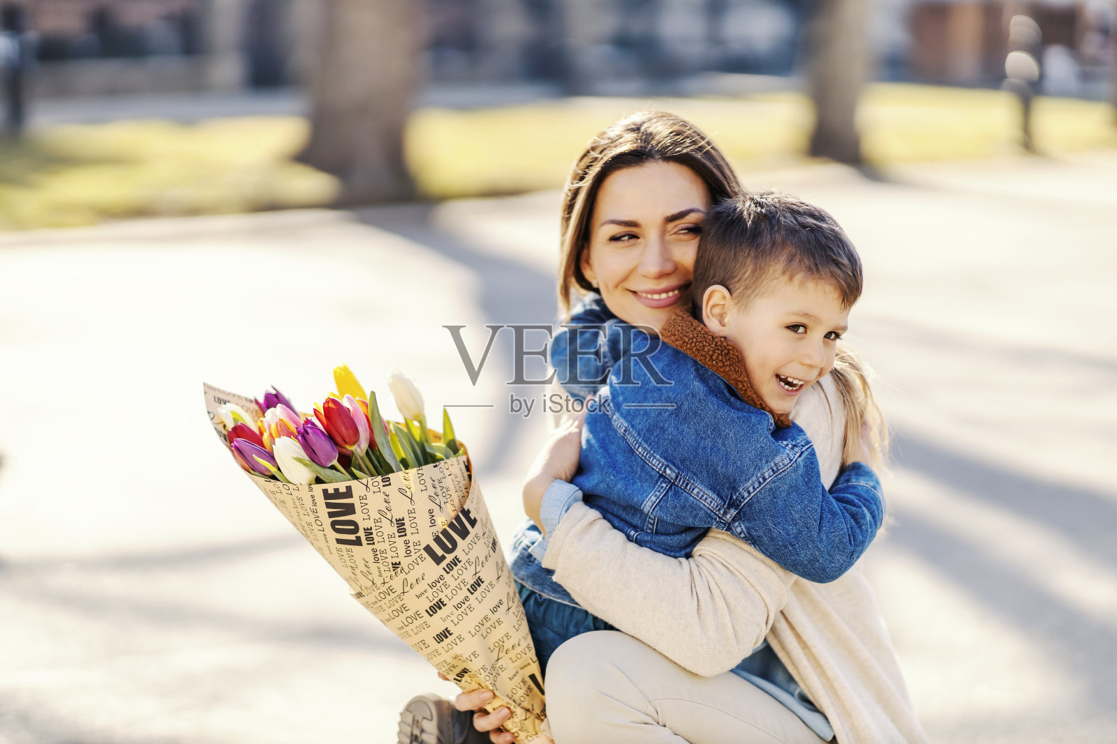 母亲节，快乐的母亲和儿子拥抱鲜花照片摄影图片