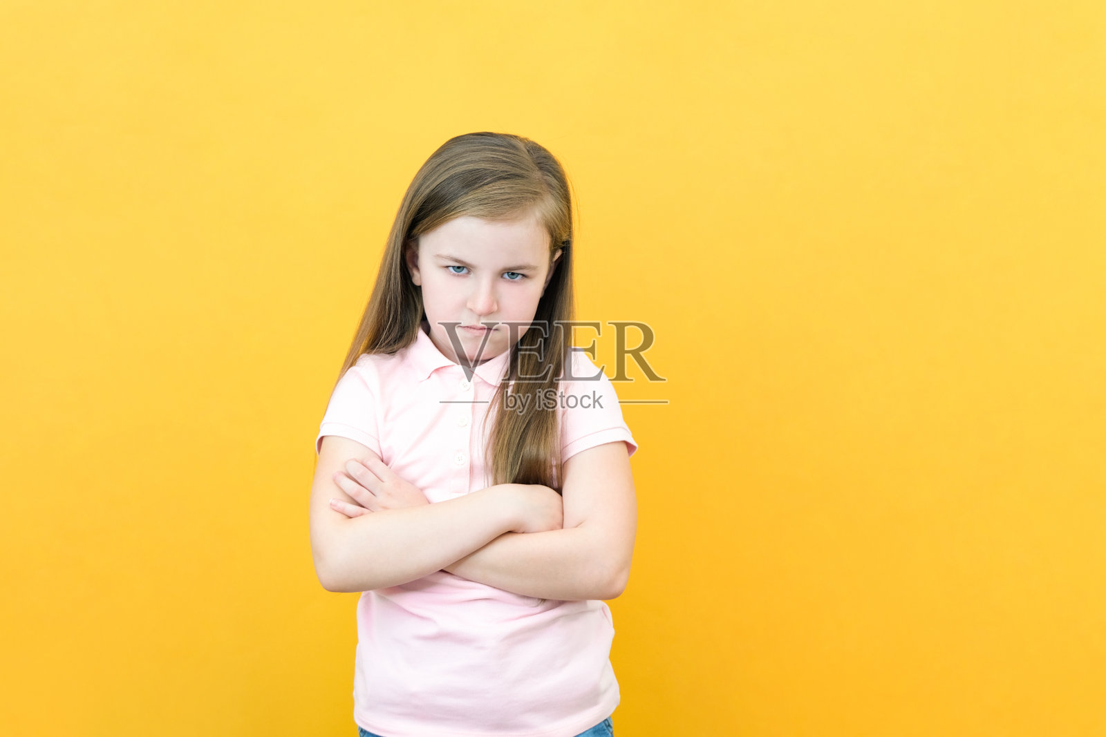 顽皮的孩子。反抗的问题。纪律处罚。可爱的愤怒被冒犯的小女孩的肖像在白色与交叉的手臂孤立在黄色的拷贝空间照片摄影图片