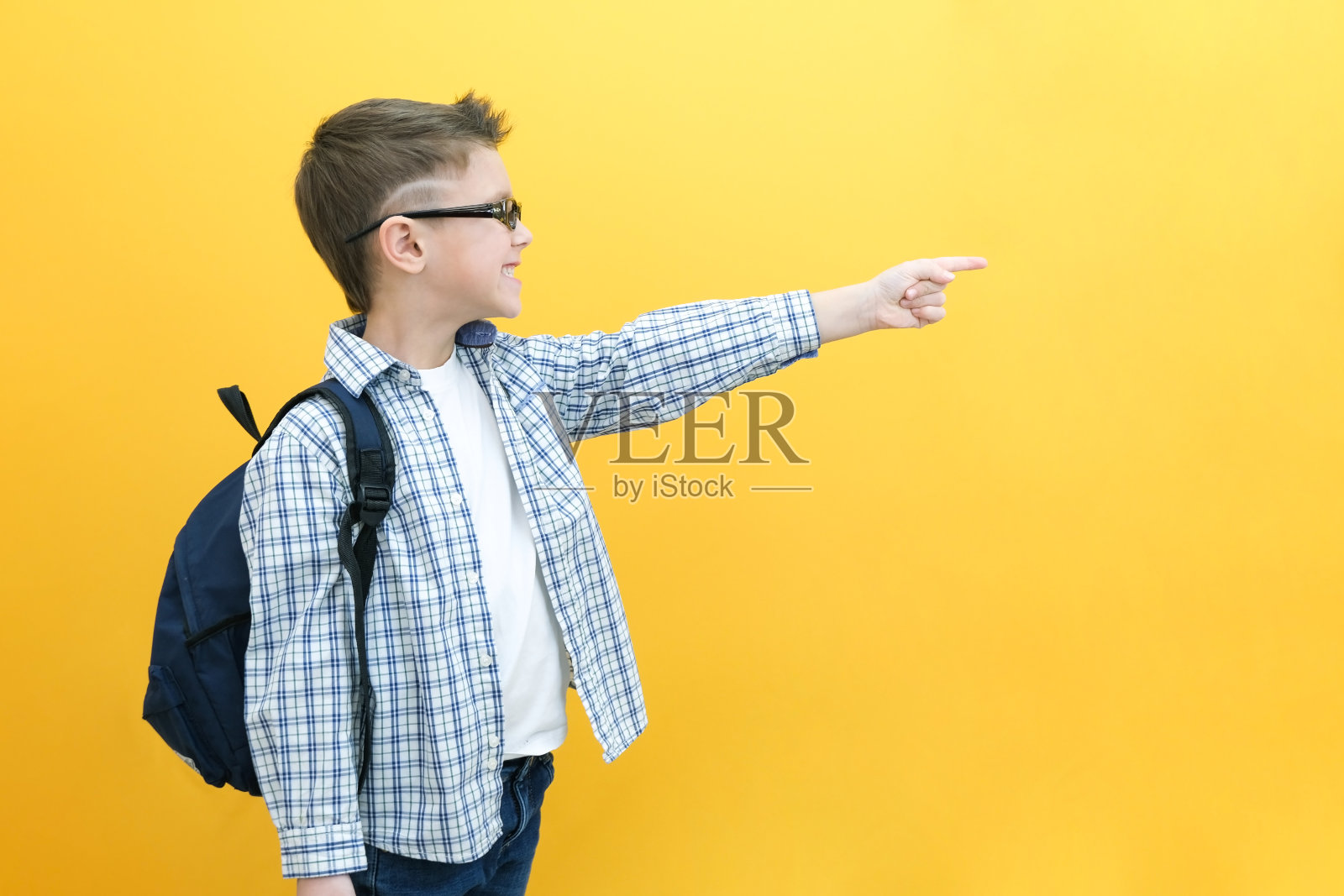 开朗，快乐的孩子点起来，为文字复制空间。微笑着，热情的学生穿着格子衬衫炫耀。广告照片摄影图片