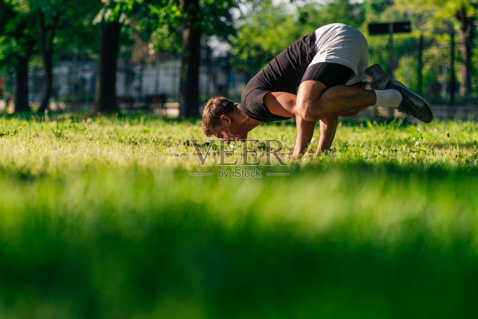 运动的年轻人在户外公园里练习乌鸦式或瑜伽体式照片摄影图片
