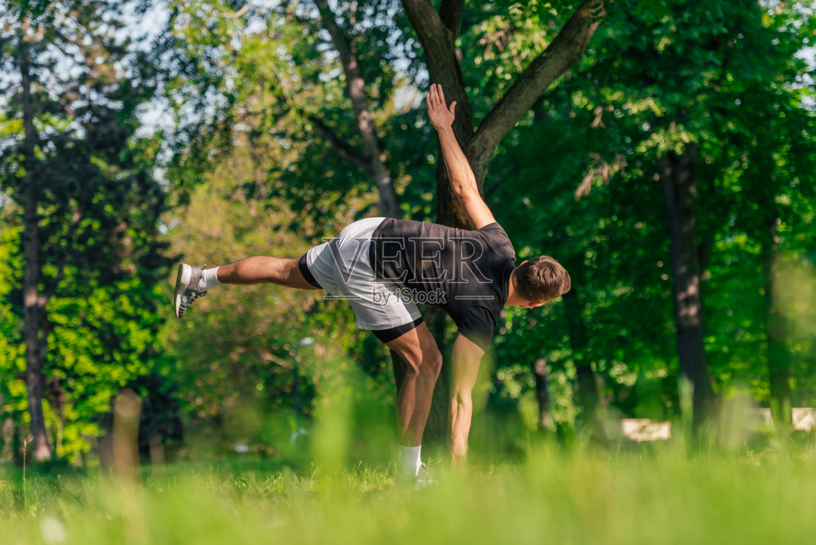 有吸引力的白人年轻男子伸展和做瑜伽练习在绿色的草地在公园照片摄影图片