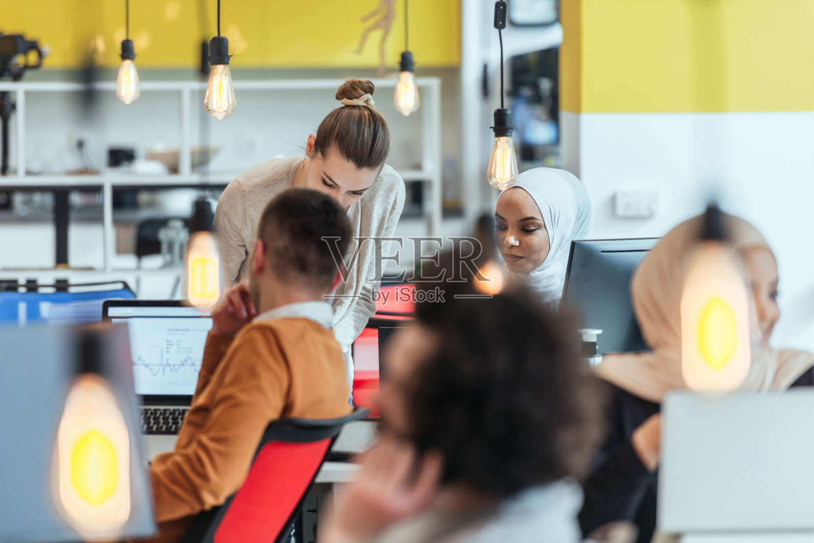 一群同事，队友帮助他们的非裔美国人，黑人，穆斯林同事戴着希贾布融入现代公司。在现代初创公司的多种族同事。照片摄影图片