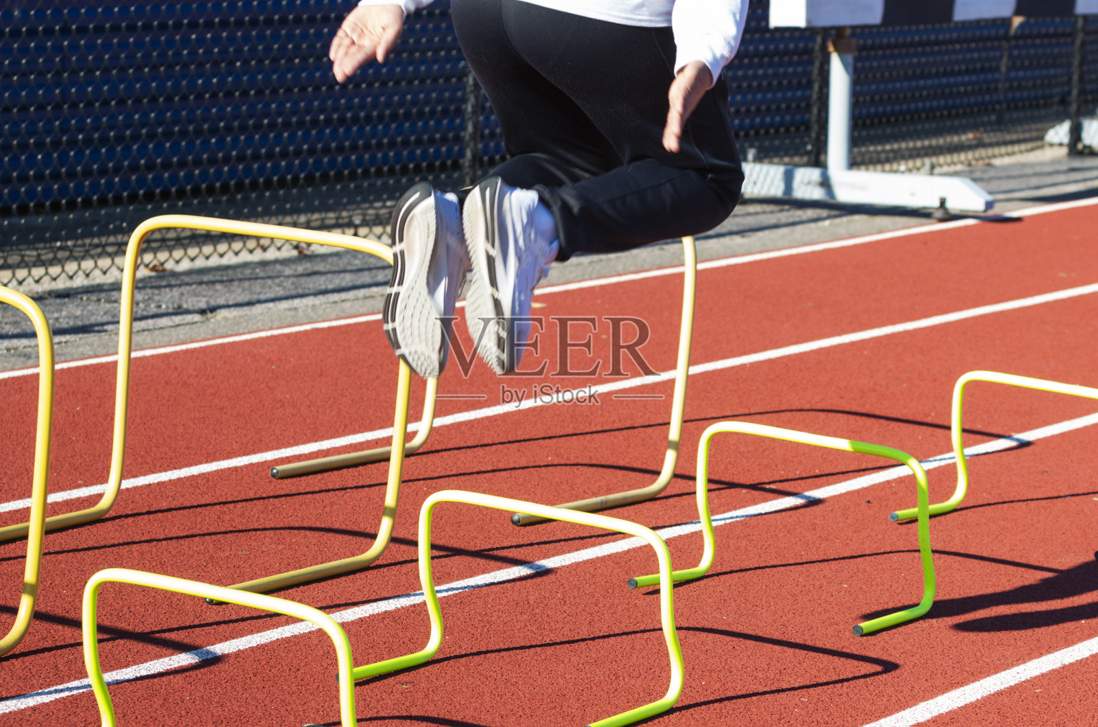 运动员在跑道上跳过黄色的小栏照片摄影图片