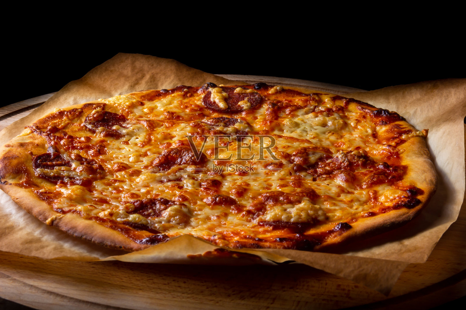 热披萨放在烤纸上，木盘上照片摄影图片