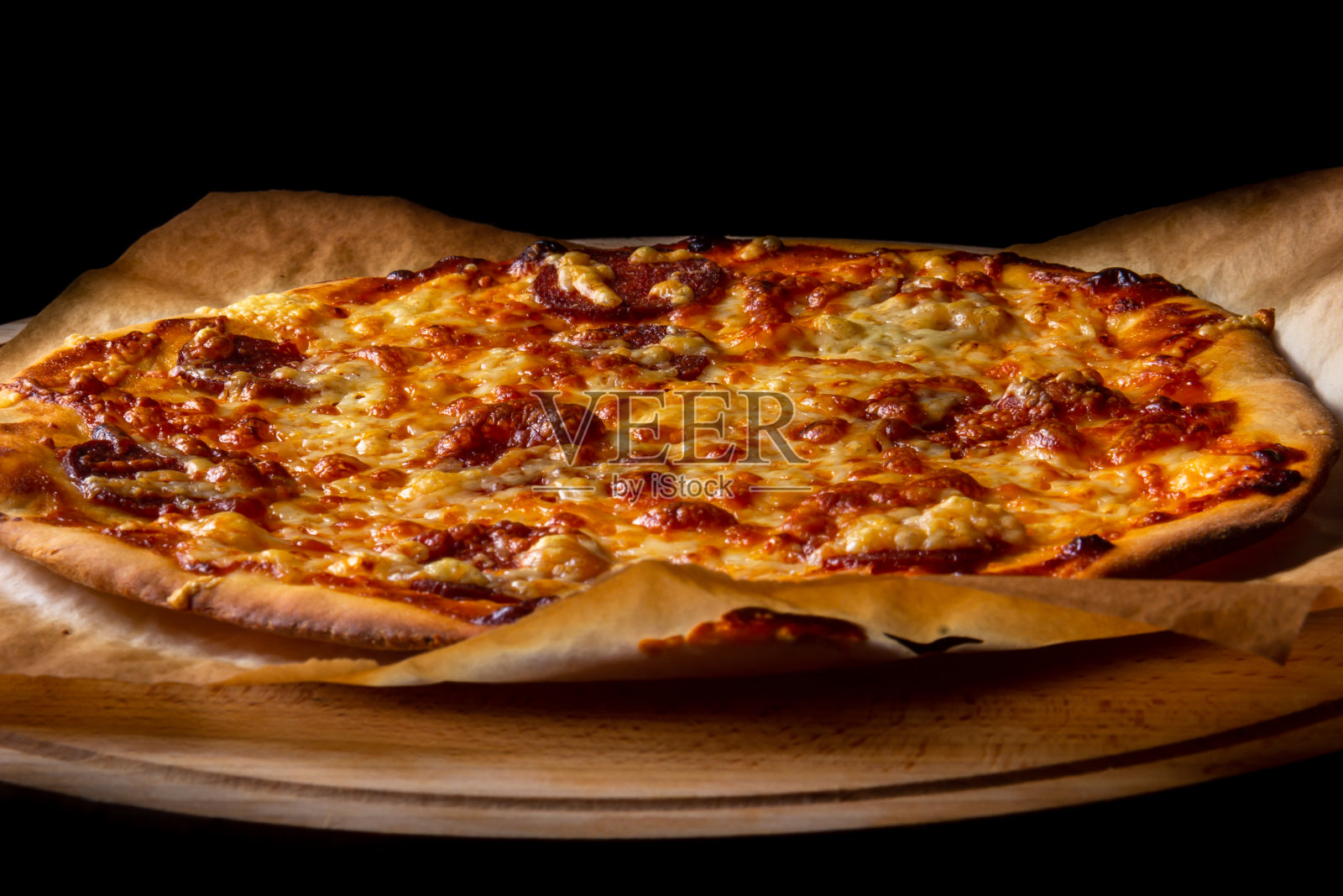 热披萨放在烤纸上，木盘上照片摄影图片