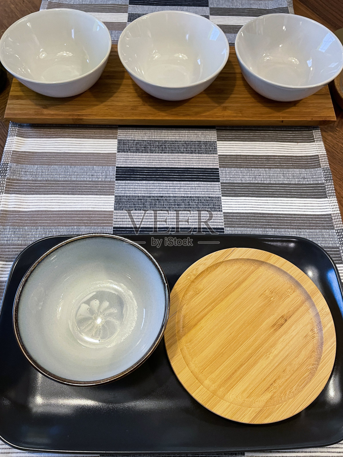 木质厨房餐桌的特写图像，由橡木制成，早餐/午餐/晚餐与白色盘子和盘子上的黑色托盘，编织的地方垫，高架视图照片摄影图片