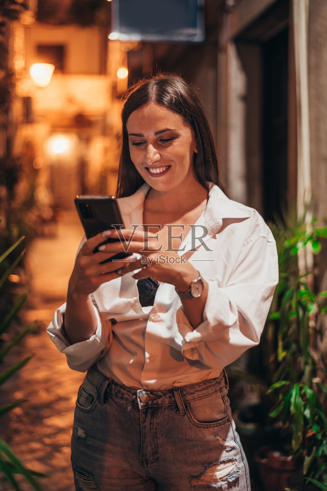 美丽的年轻女子使用智能手机行走在城市街道上的海岸在夜间照片摄影图片