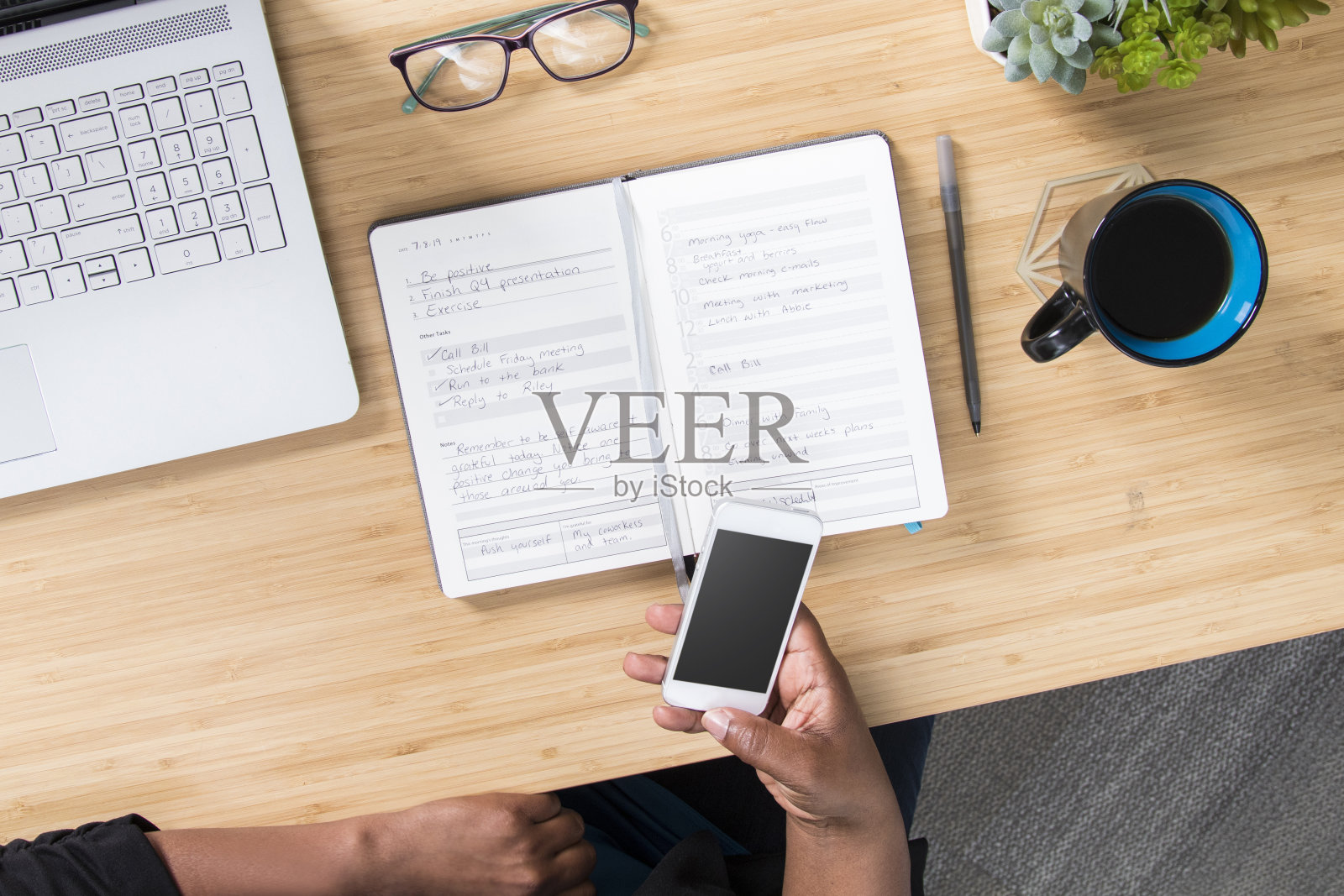 一个女人在办公室的桌子上用笔记本记事本，用手机和电脑照片摄影图片