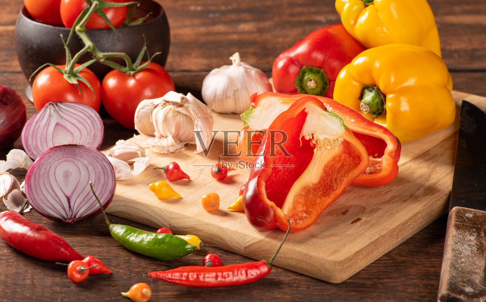 餐桌上用红、黄辣椒、辣椒、洋葱、大蒜和番茄，覆以质朴的木纹，黑色背景，选择性聚焦。照片摄影图片