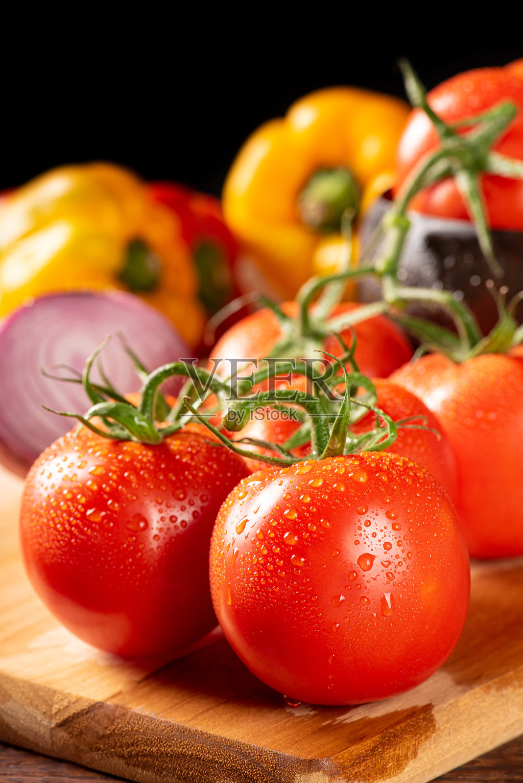 餐桌上用红、黄辣椒、辣椒、洋葱、大蒜和番茄，覆以质朴的木纹，黑色背景，选择性聚焦。照片摄影图片